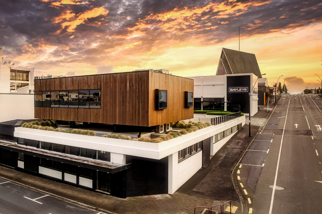 High angle shot of a two-storey architecturally designed building on a street corner with the sunset behind | VOID New Plymouth Architects
